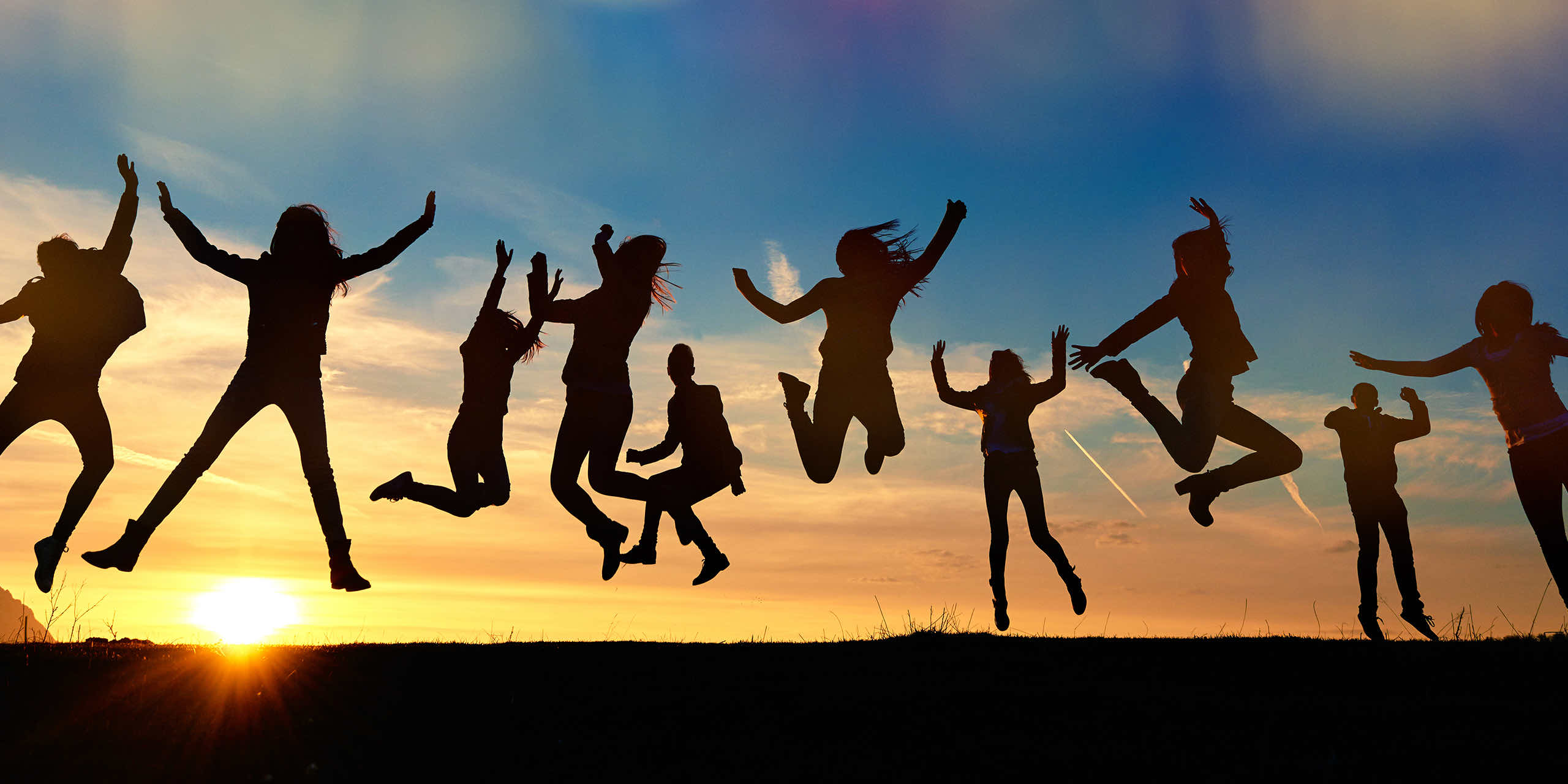 Group of people silhouetted jumping at sunset