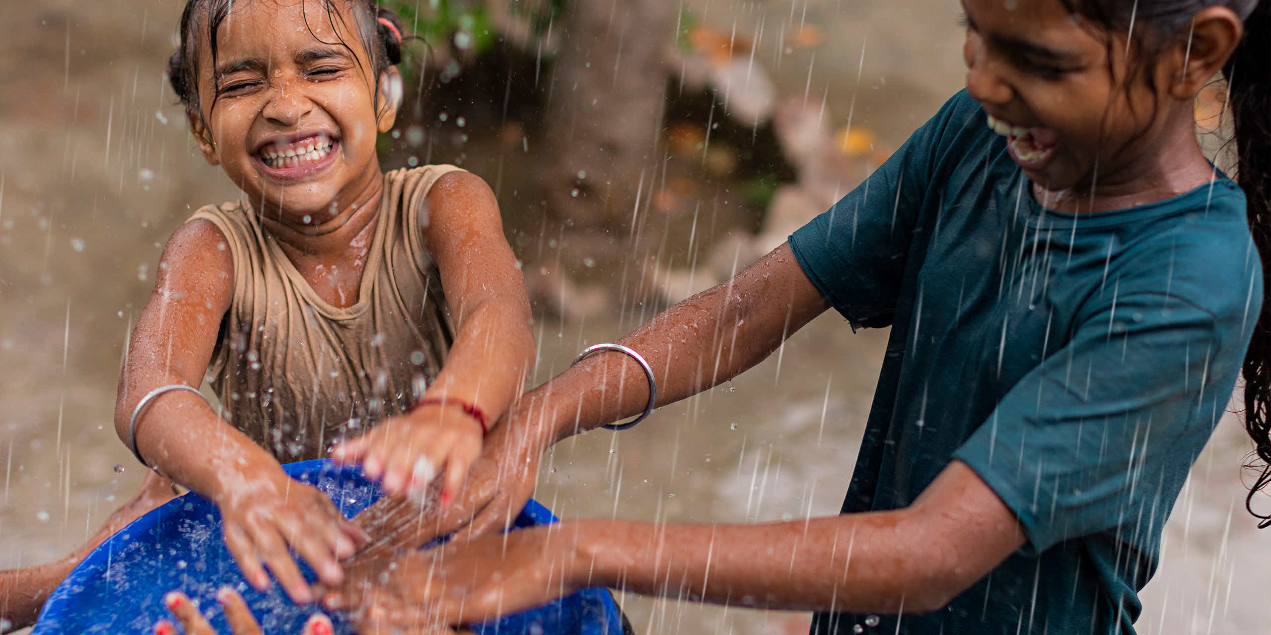 Two girls laughing while playing in the rain